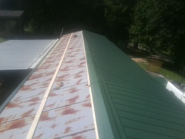 Old rusted panels beside newly installed green metal roofing — Wind Damage Roof Repair by Roofing Brothers in Fruitland