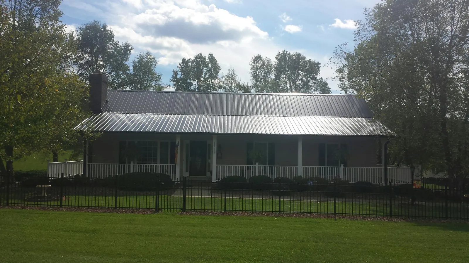 Gray metal roof on a brick ranch with a full width front porch — Gutter Guard Installation work by our crew in Fruitland