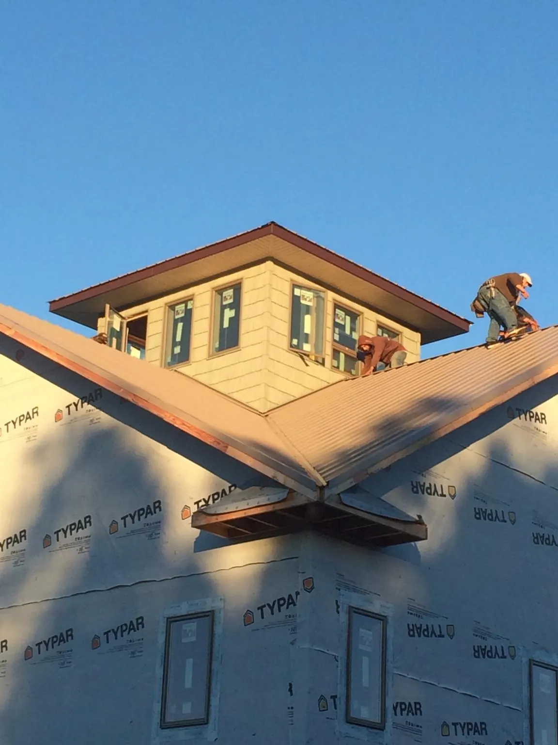 Roofers working around a rooftop cupola on a new metal roof at sunset — Roof Waterproofing in Fruitland by Roofing Brothers